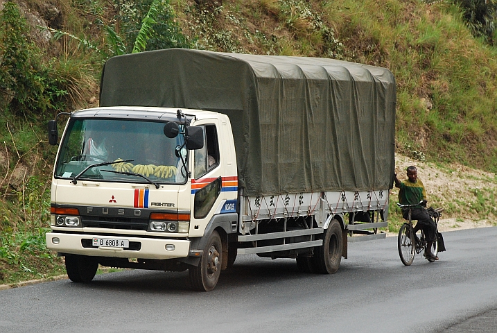 Velofahrer, der sich von einem Laster den Hügel raufziehen lässt