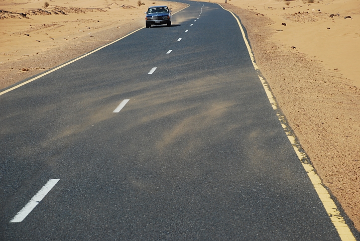 Der Wind bläst Sand über die Teerstrasse nach Abu Dom