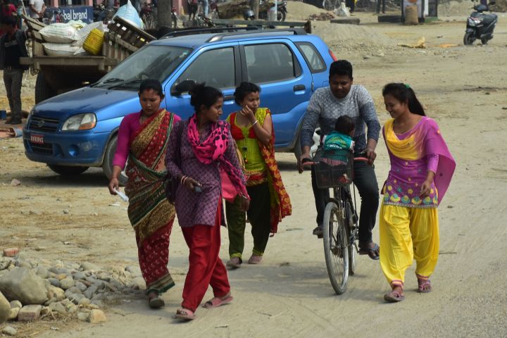 Mann mit Kind auf dem Fahrrad und vier Frauen zu Fuss im Terai