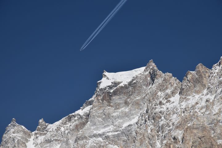 Flugzeug mit Kondenstreifen über vergletschertem Gipfel in der Nähe von Pasu im Hunza Tal