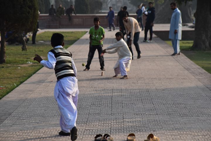 Jungen spielen Cricket im Garten des Jahangir-Mausoleums in Lahore