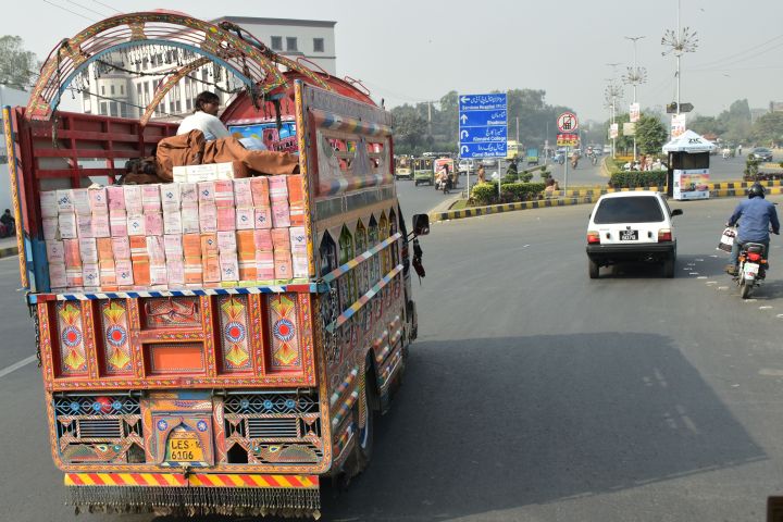 Schlafender Mann auf der Ladung eines Transporters im Morgenverkehr