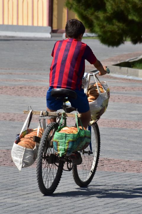 Junge auf Fahrrad mit einer Ladung Brote zur Auslieferung