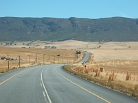 Links und rechts der Strasse abgeerntete Weizenfelder